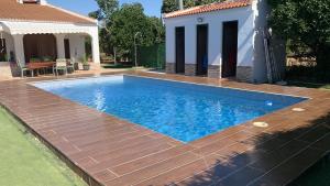 a swimming pool with a wooden deck next to a house at Casa Rocio in Aznalcázar