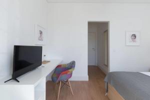 een witte kamer met een tv en een bed en een stoel bij GuestReady - Costa Cabral Guesthouse Room 4 in Porto