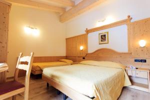 um quarto com duas camas e uma cadeira. em Hotel Majorka em Andalo