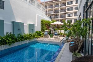 a swimming pool with two chairs and a building at Volar Hoi An in Hoi An