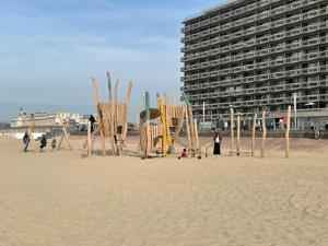 a beach with a building and some people on the sand at Residentie Aldis in Ostend