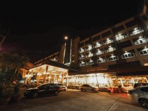 un bâtiment avec des voitures garées devant lui la nuit dans l'établissement Garden View Betong Hotel, à Betong