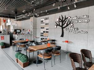 a restaurant with tables and chairs and a tree on the wall at Garden View Betong Hotel in Betong