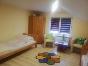 a bedroom with a bed and two chairs and a window at Kwatera Na Rogu in Augustów