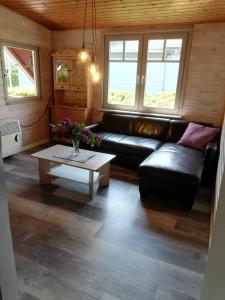 sala de estar con sofá de cuero negro y mesa en Hüttli en Rehburg-Loccum