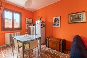 ポッツァッロにあるCasa Caterinaのオレンジ色の壁のキッチン(テーブル、冷蔵庫付)