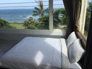 ein Schlafzimmer mit einem Bett mit Blick auf das Meer in der Unterkunft Donghe surf shop & Hostel in Donghe