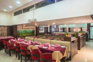 a dining room with tables and chairs with pink napkins at Yogi Broadway in Mumbai