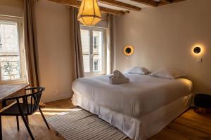 Un dormitorio con una gran cama blanca y una mesa en Les Nids Perchés - Rue Sainte Croix en Mortagne-au-Perche