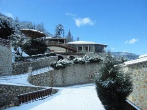 a house covered in snow with a stone wall at eco oneiro resort in Kalavrita