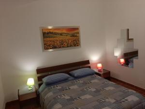 a bedroom with a bed with two lamps and a painting at Il Corbezzolo in Paciano