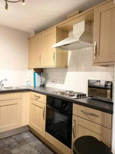 a kitchen with wooden cabinets and a black stove top oven at BEST PRICE! Huge 1 bed Apartment, City Centre, Single Beds or Super King, Sofabed & FREE SECURE PARKING in Southampton