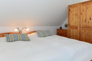 Schlafzimmer mit einem weißen Bett und einem Holzschrank in der Unterkunft Haus Albatros Whg 04 in Wyk auf Föhr