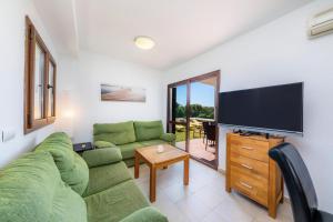 a living room with a green couch and a flat screen tv at LA PERLA DE CALA DOR in Portopetro