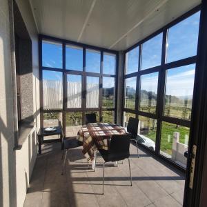 ein Raum mit Tisch und Stühlen und Fenstern in der Unterkunft Casa Xesteira Cambados in Cambados