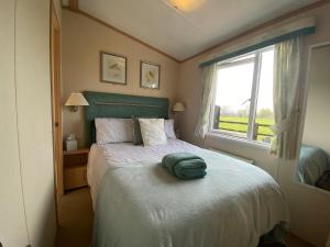 a bedroom with a bed with a green pillow on it at Rew Farm Country and Equestrian Accommodation - Sunset Lodge in Melksham