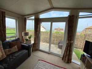 a living room with a couch and a large window at Rew Farm Country and Equestrian Accommodation - Sunset Lodge in Melksham