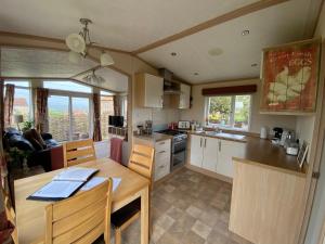 a kitchen and living room with a table and a dining room at Rew Farm Country and Equestrian Accommodation - Sunset Lodge in Melksham