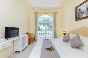 a living room with a white bed and a television at Palm Villa 18 - Biệt Phủ Hướng Biển in Vung Tau