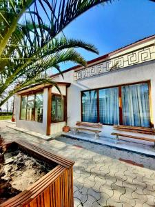 a house with a bench and a palm tree at Vila Miluna in Mamaia