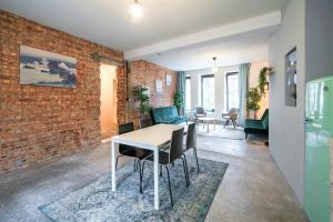 comedor con pared de ladrillo, mesa y sillas en The Industrial Apartments, en Amberes