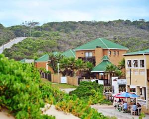 a group of buildings with people sitting under an umbrella at Seaside Vacation Studio @ Shearwater Myoli Beach in Sedgefield
