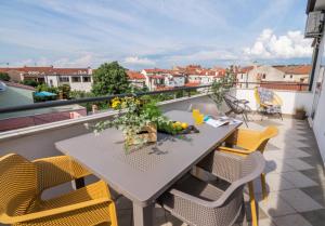 einen Tisch auf einem Balkon mit gelben Stühlen in der Unterkunft City Garden Apartment in Poreč