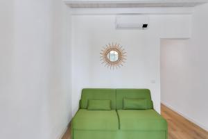 a green couch in a room with a mirror on the wall at Maison d'Orange - La Pinede in Saint-Tropez