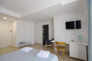 Habitación blanca con cama, escritorio y TV. en Affittacamere Aria Di Mare, en Paestum