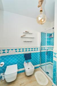 Baño de azulejos azules con aseo y lavamanos en Isola Rossa Beach House, en Isola Rossa