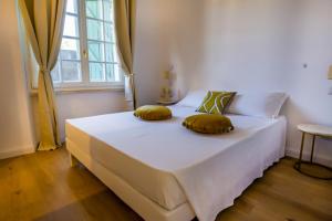 a bedroom with a white bed with two pillows on it at Maison d'Orange - La Pinede in Saint-Tropez
