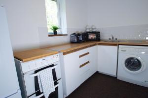 cocina con armarios blancos, lavadora y secadora en Central studio in quiet area, en Newbury