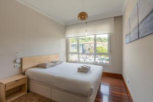 a white bedroom with a bed and a window at Zubia apartment by People Rentals in Bilbao