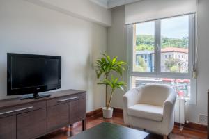 a living room with a flat screen tv and a chair at Zubia apartment by People Rentals in Bilbao