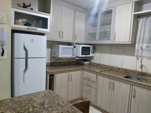 a kitchen with a white refrigerator and a microwave at Edificio Fernanda in Porto Belo