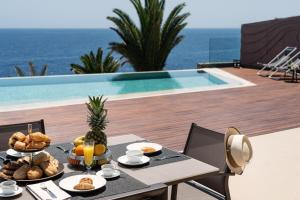 una mesa con comida junto a una piscina en SERENITY by Buenavilla, en Puerto Calero
