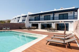 Un hotel con piscina y sillas y un edificio. en SERENITY by Buenavilla, en Puerto Calero