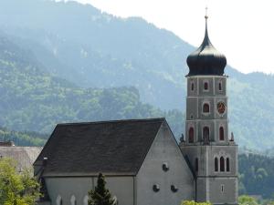 une église avec une tour d'horloge en face d'une montagne dans l'établissement Kleine feine Wohnung in Toplage, à Bludenz