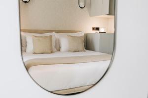 a bedroom with a bed with white pillows in a mirror at Dock 1 Boutique Hotel in Cospicua