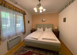 Schlafzimmer mit einem Bett, einem Fenster und einem Kronleuchter in der Unterkunft Pension Sedlak in Millstatt