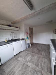 a kitchen with white appliances and a wooden floor at Ferienwohnung Dölzig in Schkeuditz