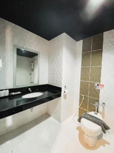 a bathroom with a toilet and a sink and a mirror at Garden View Betong Hotel in Betong