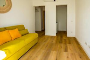 a living room with a yellow couch and wooden floors at Maison d'Orange - La Pinede in Saint-Tropez