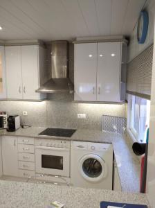 a kitchen with white cabinets and a washing machine at Maria Guerrero Cala el Pato in Cabo de Palos