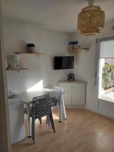 eine Küche mit einem Tisch und Stühlen sowie einem TV in der Unterkunft Logement entier : appartement en résidence in Les Sables-dʼOlonne