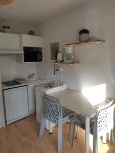 eine kleine Küche mit einem Tisch und Stühlen in der Unterkunft Logement entier : appartement en résidence in Les Sables-dʼOlonne
