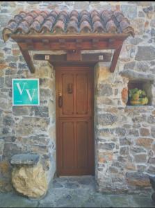 eine Holztür in einem Steingebäude mit einem Dach in der Unterkunft Casa Rural El Cotu en Cangas de Onís in Cangas de Onís
