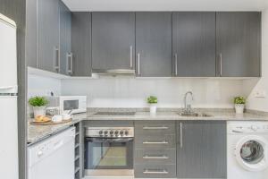 Una cocina con gabinetes grises y un fregadero. en CONFORT APARTMENT, en Roses