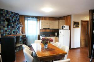 cocina con mesa de madera y electrodomésticos blancos en Casa vacanze Valle d'Aosta - Maison Lugon, en Aosta