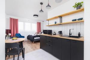 cocina con armarios negros y mesa y sala de estar en Apartments Kraków Czarnowiejska by Renters, en Cracovia